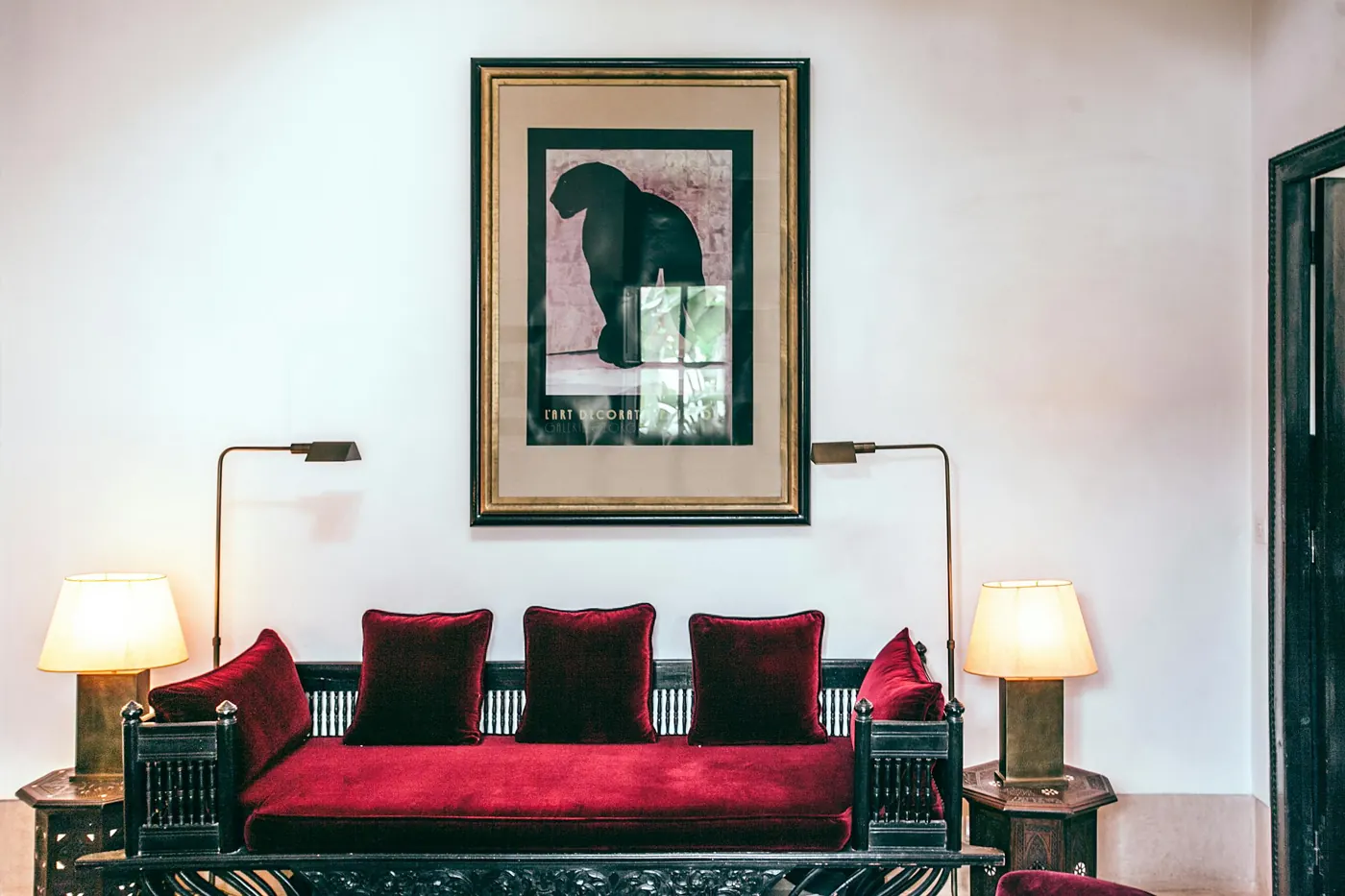 Salon de réception : banquette en velours rouge, lampes et gravure encadrée